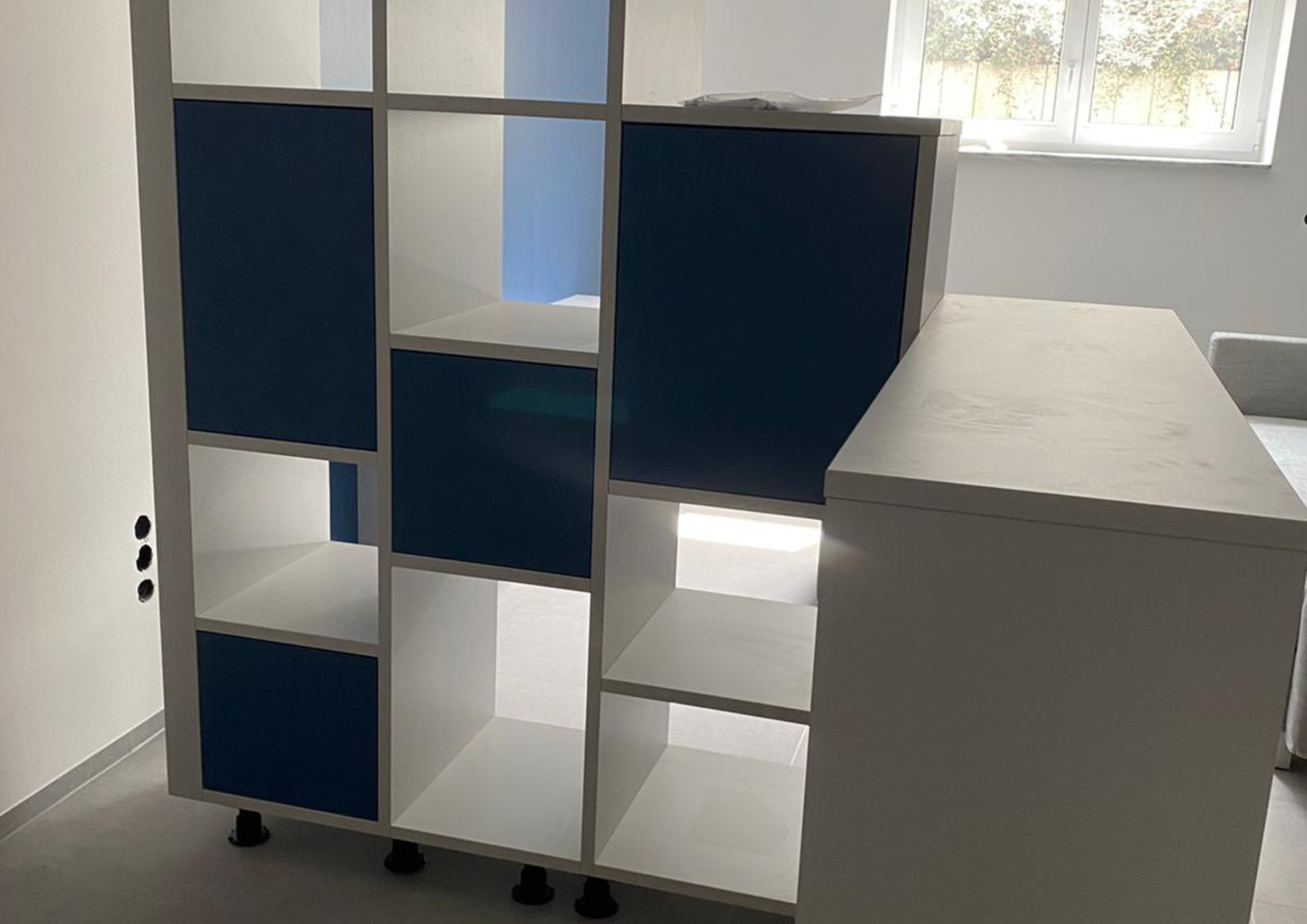 Raumteiler-Regal mit blauen und weißen Fächern in modernem Wohnraum