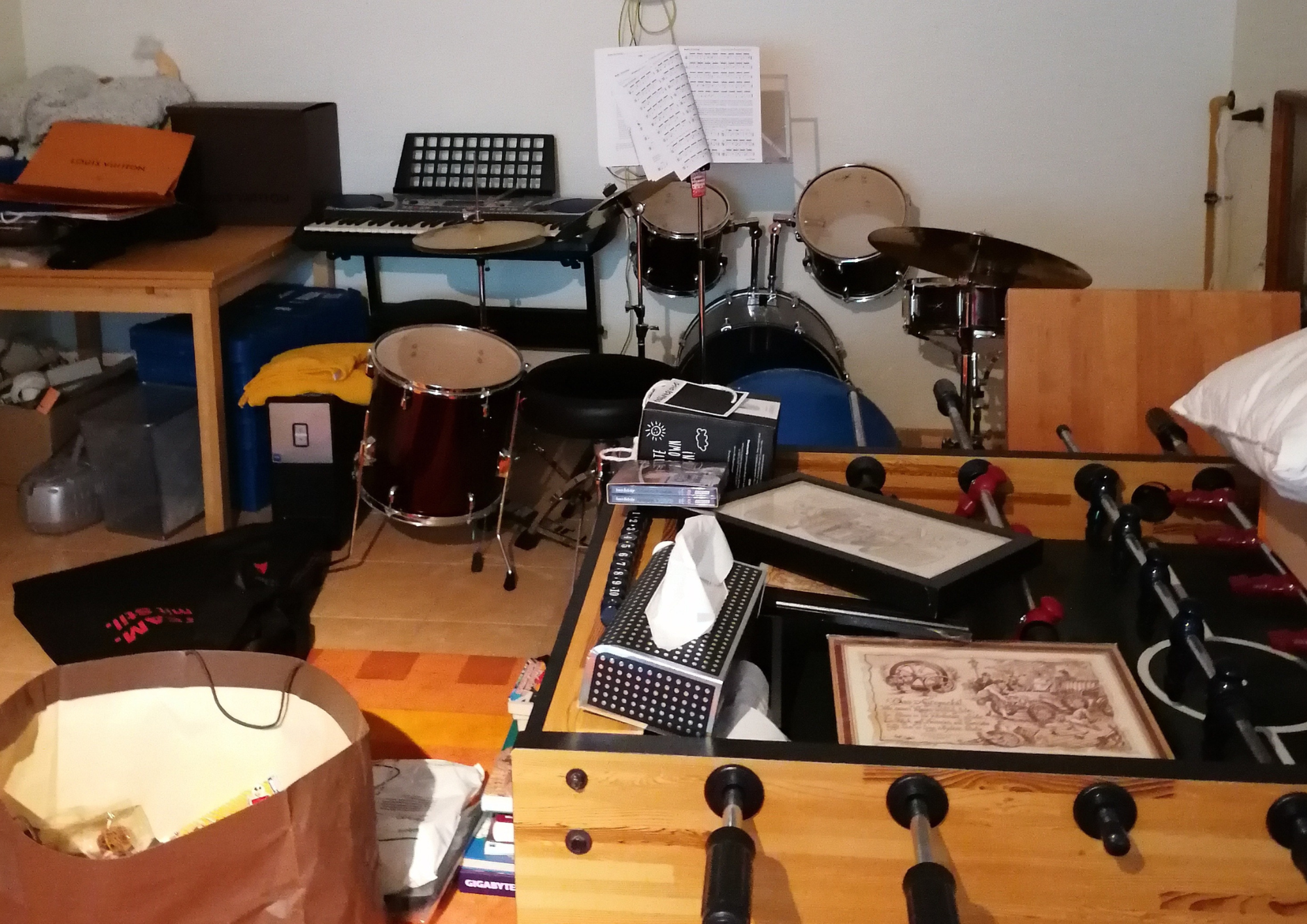 Musikzimmer mit Schlagzeug, Keyboard und Tisch voller Gegenstände