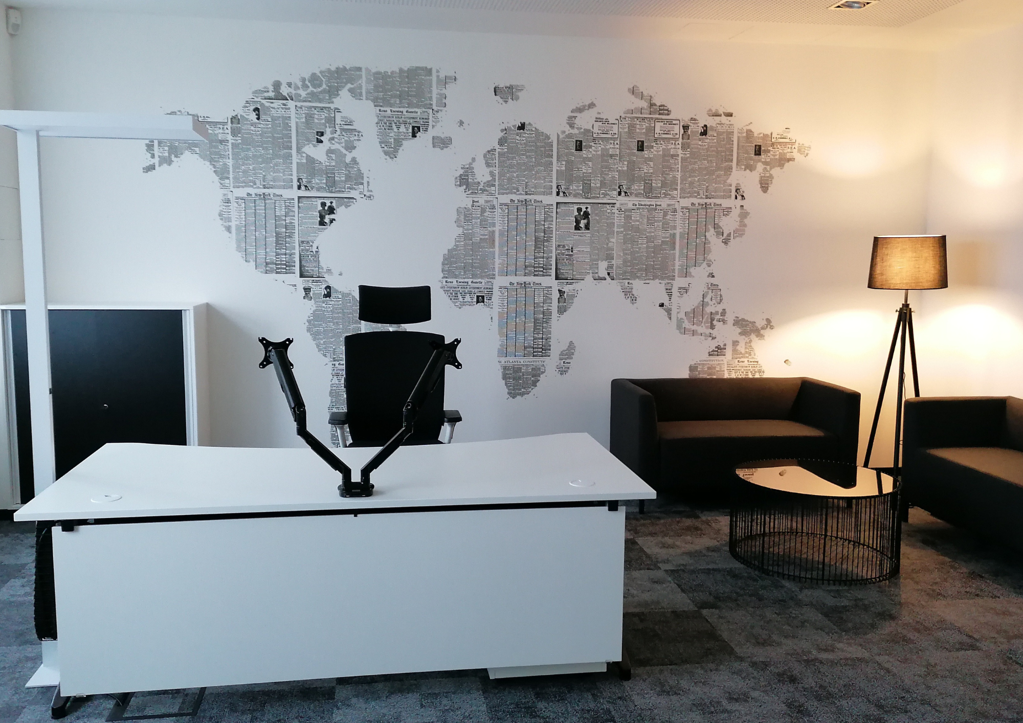 Modern eingerichteter Büroraum mit Zeitungsausschnitt-Weltkarte an der Wand und Lounge-Ecke