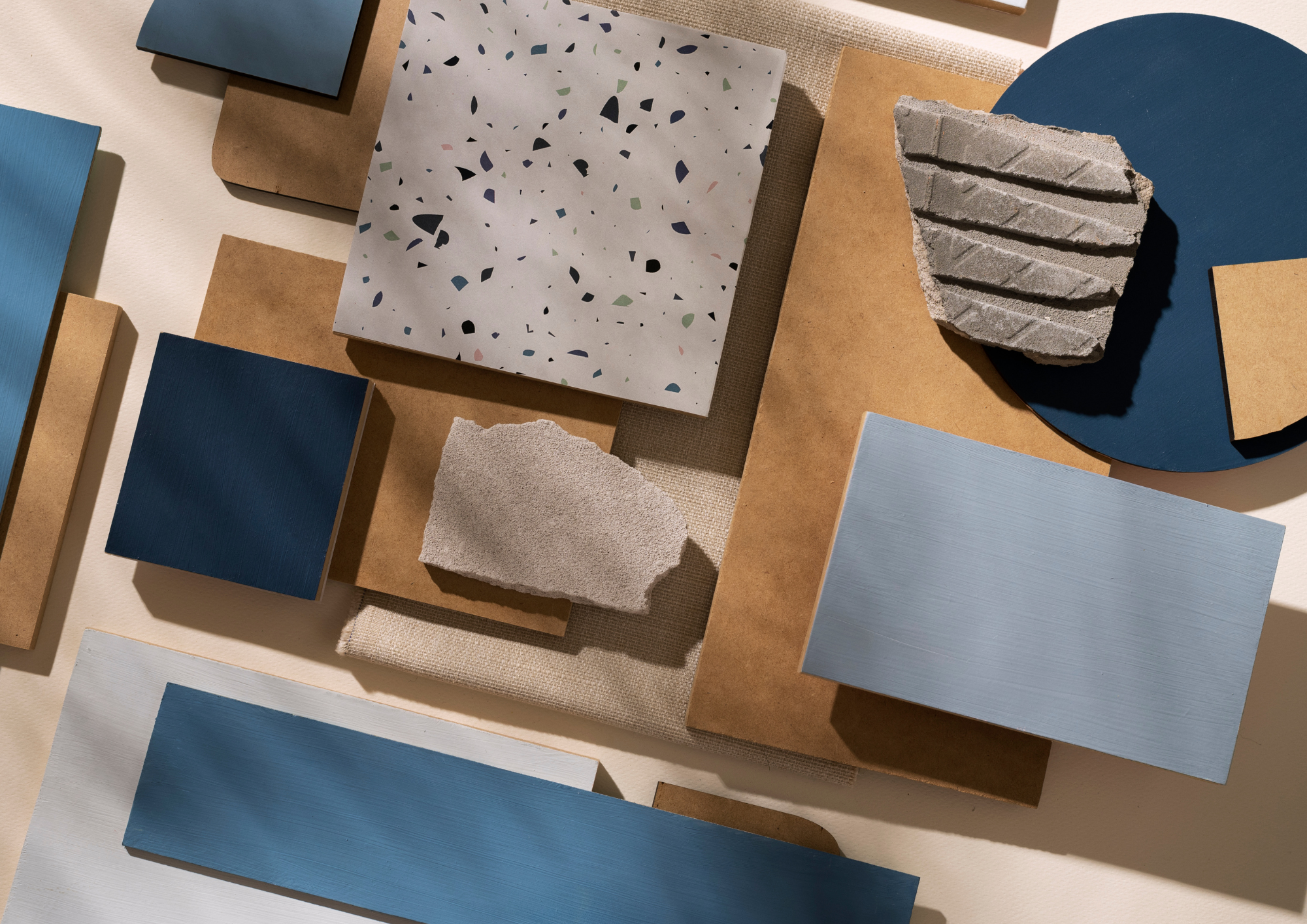 Farb- und Materialmuster aus Holz, Stein und Terrazzo in Blau- und Naturtönen, von oben fotografiert