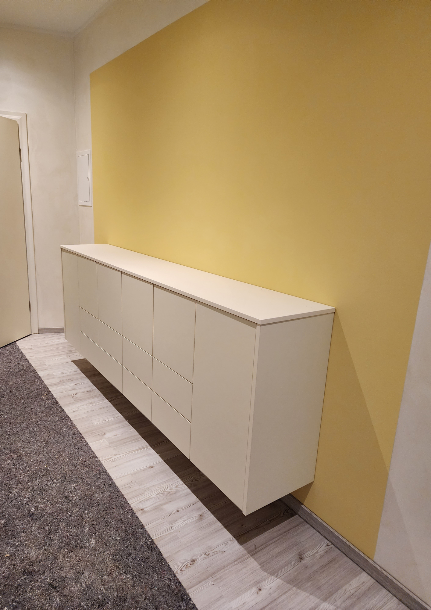 Neuer Flur mit gelber Wand und weißem Einbauschrank nach der Renovierung.