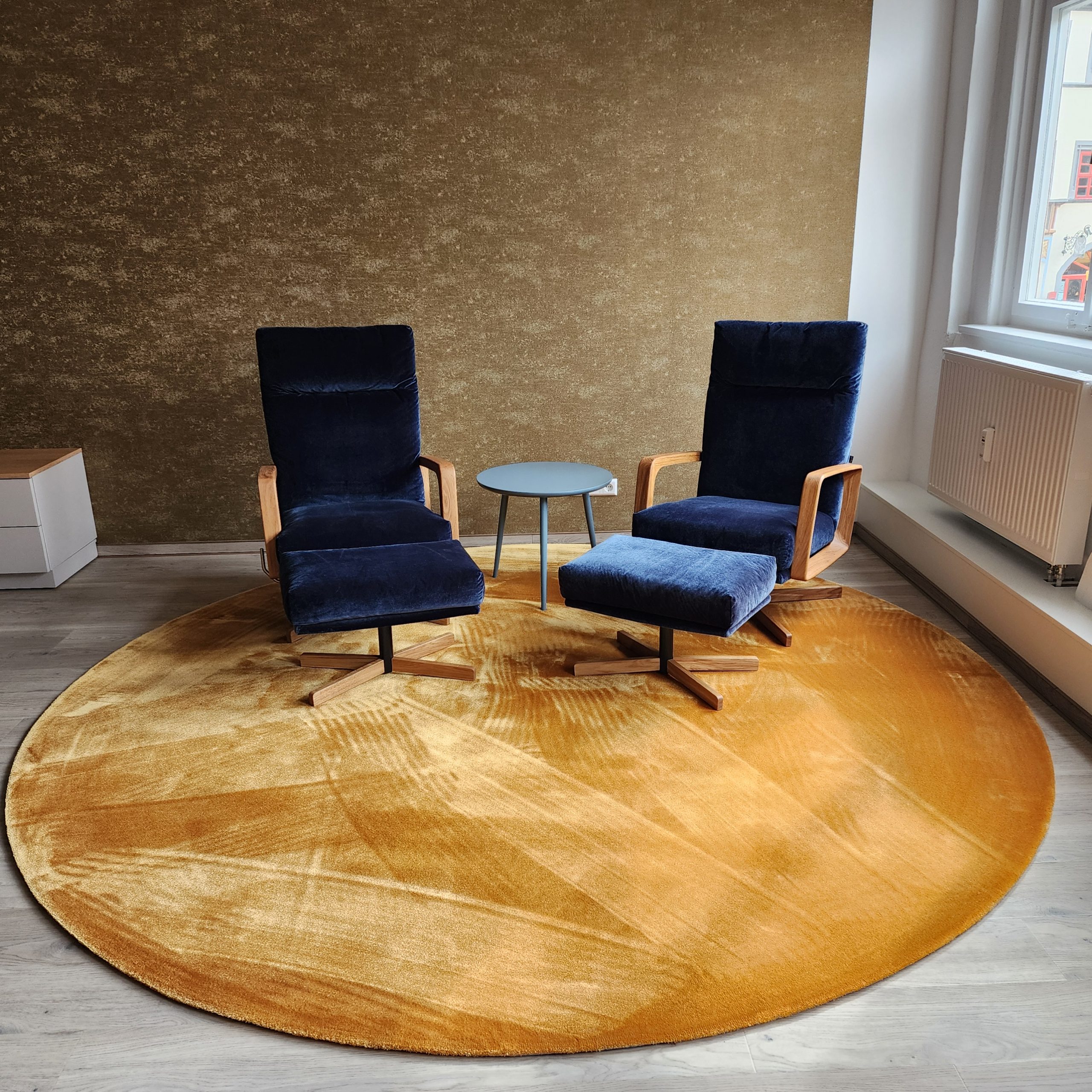 Stilvoller Sitzbereich mit zwei blauen Sesseln und senfgelbem Teppich in einem renovierten Altbau in Leipzig – modernes Raumdesign in historischer Umgebung.